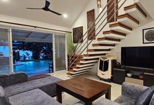 a living room with a staircase and a television at Villa Emerald Sand - Beach Front 4 Bed Pool Villa in Koh Samui 