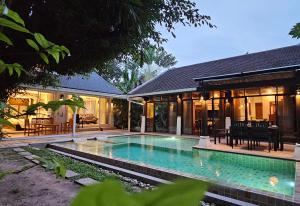 a house with a swimming pool in front of a house at Villa Emerald Sand - Beach Front 4 Bed Pool Villa in Koh Samui 