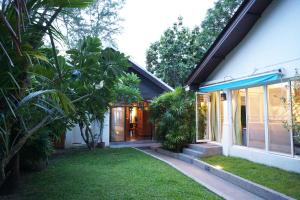 a house with glass doors and a green yard at Villa Emerald Sand - Beach Front 4 Bed Pool Villa in Koh Samui 