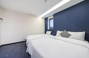 two white beds in a room with a blue wall at Adlige Hotel in Seoul
