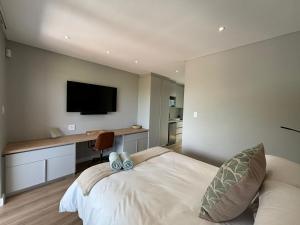 a bedroom with a bed and a desk with a television at Swanemeer Apartments in Cape Town