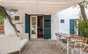 eine Terrasse mit grünen Türen sowie einem Tisch und Stühlen in der Unterkunft PETRA BIANCA Charming House in Mattinata