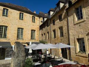 a patio with tables and umbrellas in front of buildings at Le STUDIO DUO CITE MEDIEVAL SARLAT in Sarlat-la-Canéda