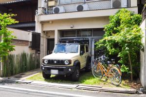 a white jeep parked in front of a building with bikes at Suzuki Guesthouse in Kyoto