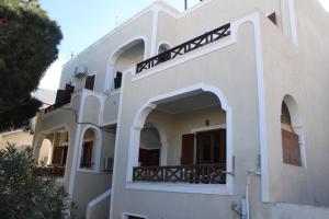 a white building with an archway and a balcony at Rodi Apartment 2 in Kamari