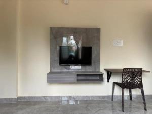 a tv on a wall with a table and a chair at Cozy Room 1Bhk with Lift 203 in Bengaluru