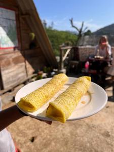 a person holding a plate with corn on the cob at Backpackers Hostel in Ella