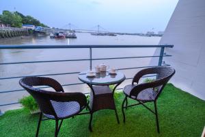 dwa krzesła i stół na balkonie z rzeką w obiekcie Polo Floatel Kolkata w mieście Kolkata