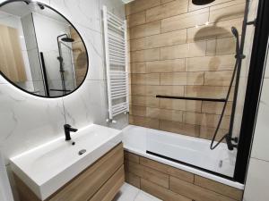 a bathroom with a sink and a tub and a mirror at Wygodne Mieszkania Nova Mikołowska Apartamenty in Katowice +15 photos