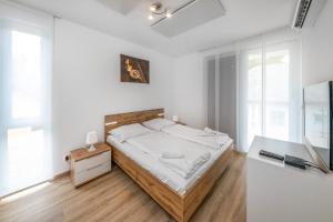 ein weißes Schlafzimmer mit einem Bett und einem TV in der Unterkunft Anchor Apartman by HelloBalatonlelle in Balatonlelle
