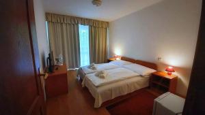 - une chambre avec un grand lit et une fenêtre dans l'établissement PSZ Hotel Beach Földvár, à Balatonföldvár