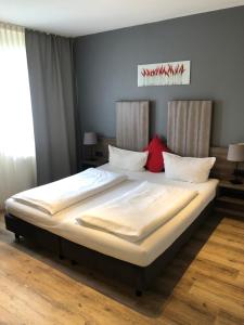 a bedroom with a large bed with white sheets and red pillows at Hotel Rahserhof in Viersen