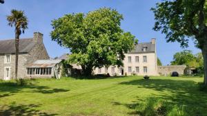 an old stone house with a tree in the yard at Gites du Manoir de Kergoniou Saint Joseph in Paimpol