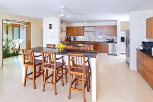 una cocina con armarios de madera, mesa y sillas en Tom Tom by Blue Sky Luxury, en Saint James