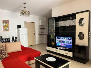 Il comprend un salon doté d'un canapé rouge et d'une télévision à écran plat. dans l'établissement Apartments Vlora Holidays, à Vlorë