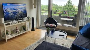 a living room with a television and a chair and a table at Diba beach stay in Kolding
