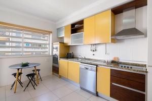 Una cocina con gabinetes amarillos y blancos y una mesa. en Apartamento Armação de Pêra, en Armação de Pêra
