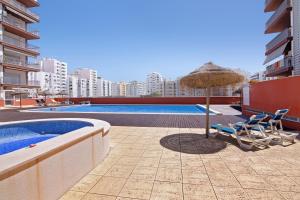 una piscina con sombrilla, 2 sillas, mesa y sombrilla en Apartamento Armação de Pêra, en Armação de Pêra