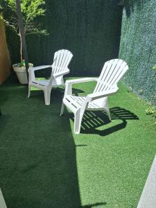 dos sillas blancas de césped sentadas en el césped en apartment garden, en Caldas de Reis