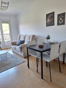 een woonkamer met een tafel en stoelen en een bank bij ATICO CALDAS in Caldas de Reis