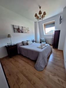 een slaapkamer met een groot bed en een kroonluchter bij ATICO CALDAS in Caldas de Reis