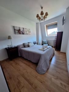 a bedroom with a large bed and a chandelier at ATICO CALDAS in Caldas de Reis