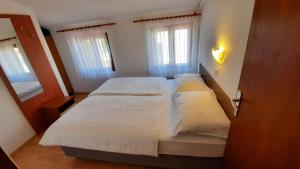a bedroom with two beds with white sheets at Apartment Pulić in Rab