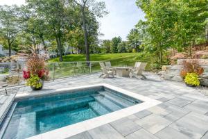 een zwembad in een patio met een tafel en stoelen bij Lakemore Resort - New Luxury Lakefront Brown House in Kingsley