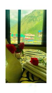 a bedroom with a bed with red roses on it at Triumph bed and breakfast and cafe in Kasol
