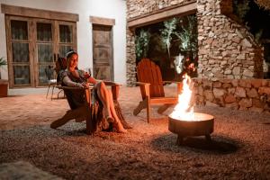 a woman sitting in a chair next to a fire at Hábimo - Valle de Guadalupe in Valle de Guadalupe