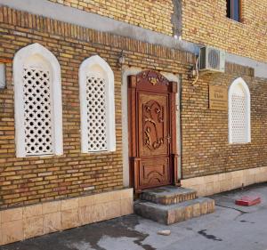 une porte en bois sur le côté d'un bâtiment en briques dans l'établissement LION Guest House, à Boukhara
