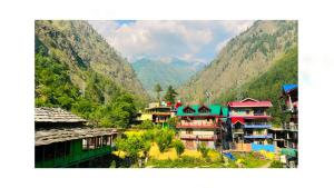 a group of buildings with mountains in the background at Triumph bed and breakfast and cafe in Kasol