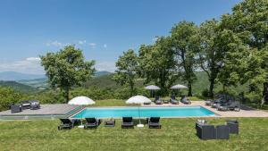 a swimming pool with chairs and umbrellas in the grass at VILLA A CASA DI GIOVANNI 12, Emma Villas in Acquapendente
