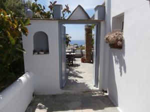 an alley in a white building with a view of the ocean at Galini Bungalows in Kionia