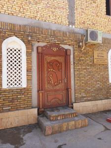 une porte en bois sur le côté d'un bâtiment en briques dans l'établissement LION Guest House, à Boukhara