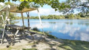 a picnic table and chairs next to a lake at Mobil Home vue sur le lac dans un camping 4 étoiles à Cadenet in Cadenet