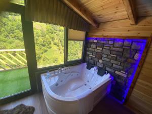 bañera grande en una habitación con ventanas en Sisorti süit bungalov en Rize