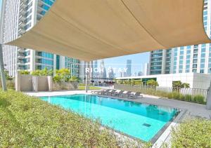 a swimming pool with a large umbrella over it at Incredible 1BR apartment, Downtown Views II by Rich Stay in Dubai
