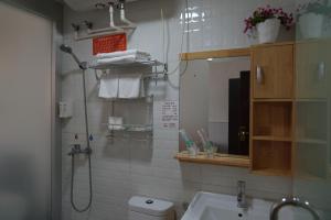 y baño con ducha, lavabo y espejo. en Jinan Mountain and Sea Culture Hotel, en Jinan
