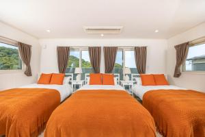 白浜町にあるホープヒルズのオレンジのシーツが備わる客室内のベッド2台