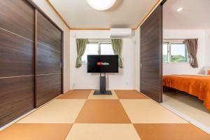 um quarto com uma televisão e um piso em xadrez em Hopehills em Shirahama