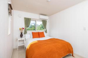 una camera da letto con un letto con una coperta arancione e una finestra di Hopehills a Shirahama