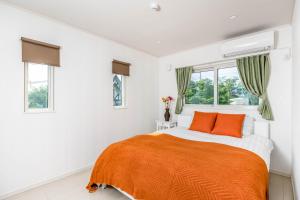 um quarto branco com uma cama laranja e janelas em Hopehills em Shirahama