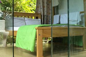 a wooden bench with a green blanket on it at Nkofu Forest Cottage - Kitende in Wakiso