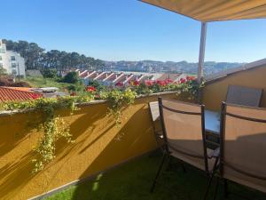 un balcón con 2 sillas y flores en el techo en Bonito apartamento en la playa, en Sanxenxo
