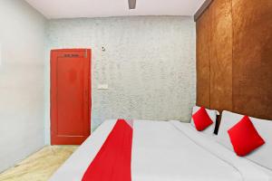 Flagship Kashish Residency في نيودلهي: غرفة نوم بباب احمر وسرير بمخدات حمراء
