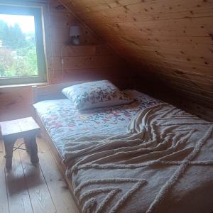 a bed in a log cabin with a window at Drewniany Domek in Bukowiec