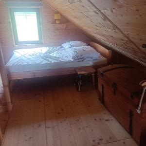 a bed in a wooden room with a window at Drewniany Domek in Bukowiec