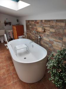 a bath tub in a bathroom with a brick wall at Apartma Hiša Pliska in Pliskovica