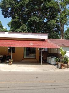 a building on the side of a street with a red roof at kamrai resort apartment in Ban Bang Bao